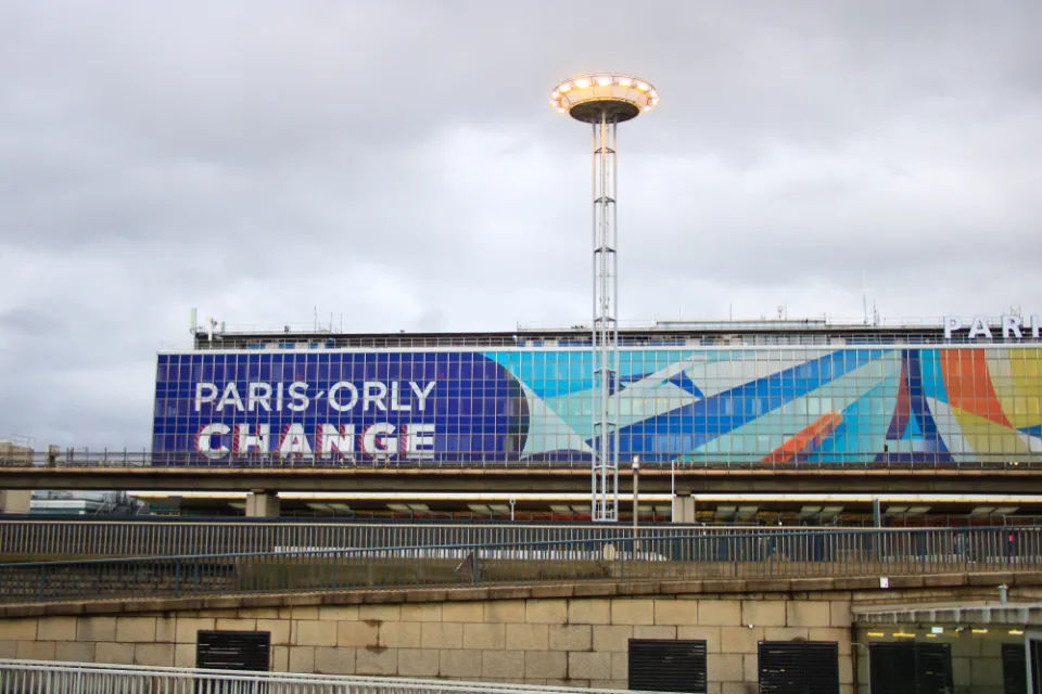 The exterior of a terminal at Orly Airport in France, with a large graphic that reads “Orly Change.”
